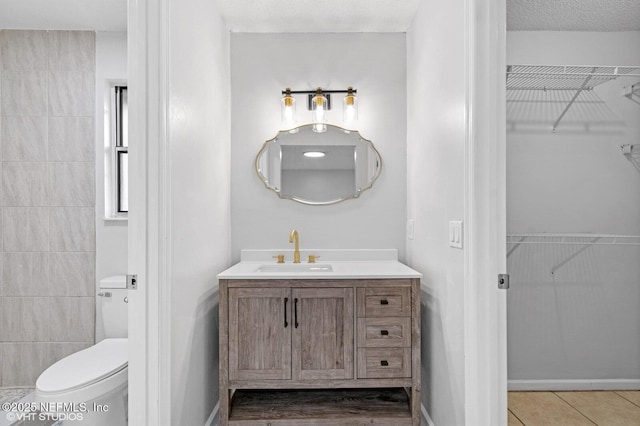 7927 Dwyer Dr, Jacksonville, FL 32244 - bathroom with a textured ceiling, toilet, tile patterned floors, vanity, and a spacious closet