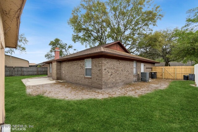 7927 Dwyer Dr, Jacksonville, FL 32244 - view of side of home featuring a chimney, brick siding, a fenced backyard, a patio, and a lawn