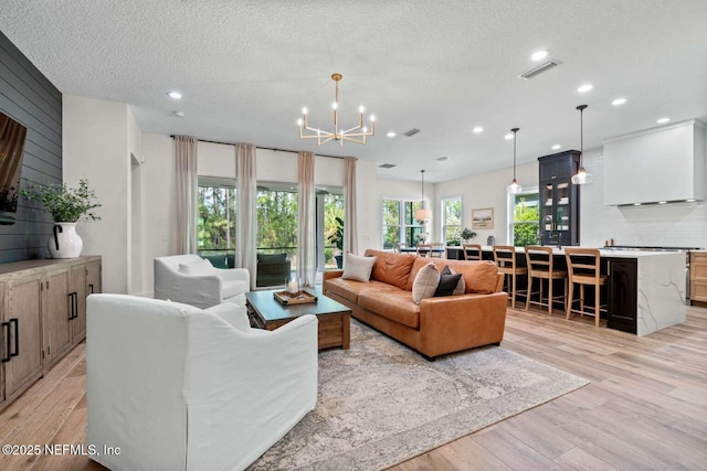 126 Seahill Dr, Saint Augustine, FL 32092 - living room with visible vents, a textured ceiling, light wood-style flooring, and a notable chandelier