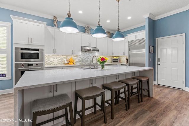 1053 Anchor Rd, Saint Johns, FL 32259 - kitchen with crown molding, under cabinet range hood, white cabinets, appliances with stainless steel finishes, and wood finished floors