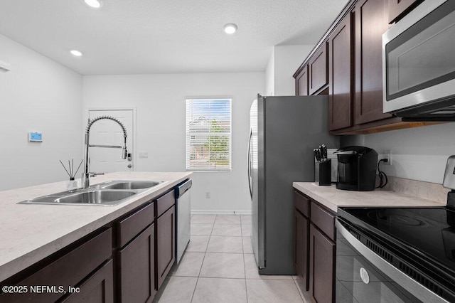 kitchen featuring light countertops, stainless steel appliances, light tile patterned flooring, a sink, and dark brown cabinetry