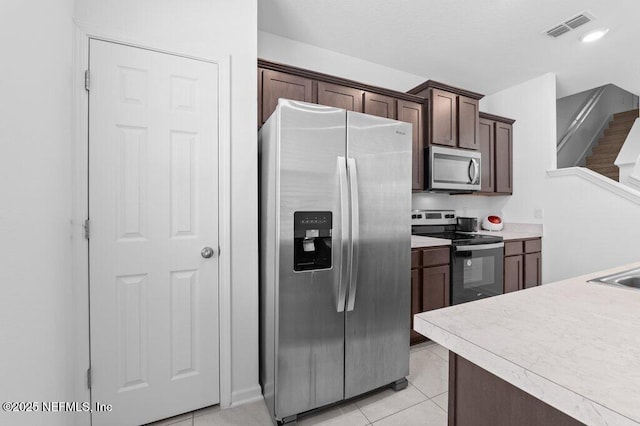 kitchen featuring light countertops, visible vents, stainless steel appliances, dark brown cabinetry, and light tile patterned floors