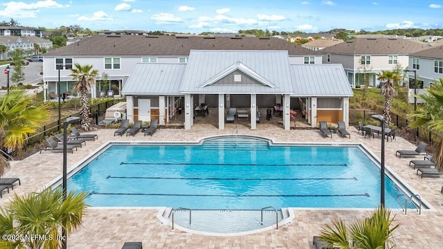 pool featuring fence, a patio, and a residential view