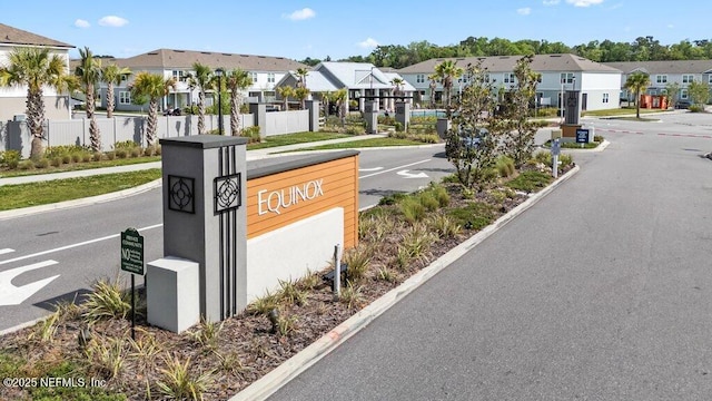 community sign featuring a residential view, uncovered parking, and fence