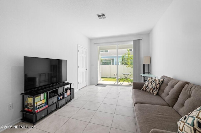 living area with a textured ceiling, visible vents, baseboards, and light tile patterned floors