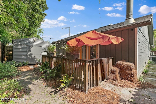 1202 Wolfe St, Jacksonville, FL 32205 - view of side of home featuring a shed, an outbuilding, fence, central AC unit, and board and batten siding
