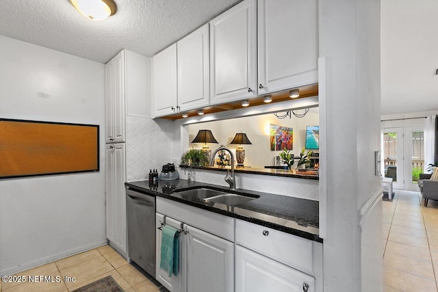 1202 Wolfe St, Jacksonville, FL 32205 - kitchen with a sink, dishwasher, light tile patterned floors, white cabinetry, and dark stone countertops