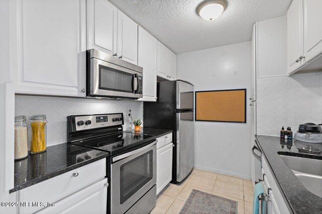 1202 Wolfe St, Jacksonville, FL 32205 - kitchen featuring stainless steel appliances, white cabinets, backsplash, a sink, and a textured ceiling