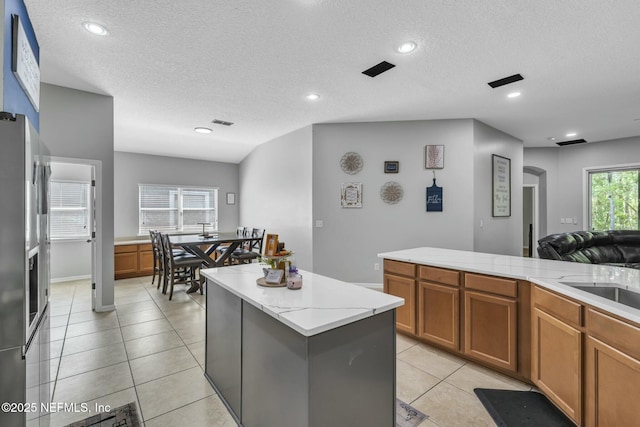 141 Casa Sevilla Ave, Saint Augustine, FL 32092 - kitchen with a center island, brown cabinets, stainless steel fridge, and a textured ceiling