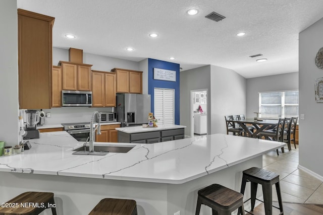 141 Casa Sevilla Ave, Saint Augustine, FL 32092 - kitchen with a sink, appliances with stainless steel finishes, a peninsula, brown cabinets, and a breakfast bar area