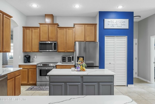 141 Casa Sevilla Ave, Saint Augustine, FL 32092 - kitchen with brown cabinets, light stone countertops, light tile patterned flooring, and stainless steel appliances