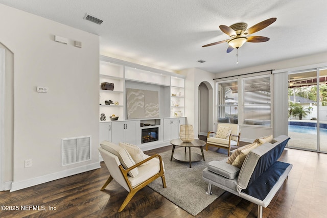 living room featuring visible vents, arched walkways, a ceiling fan, and wood finished floors