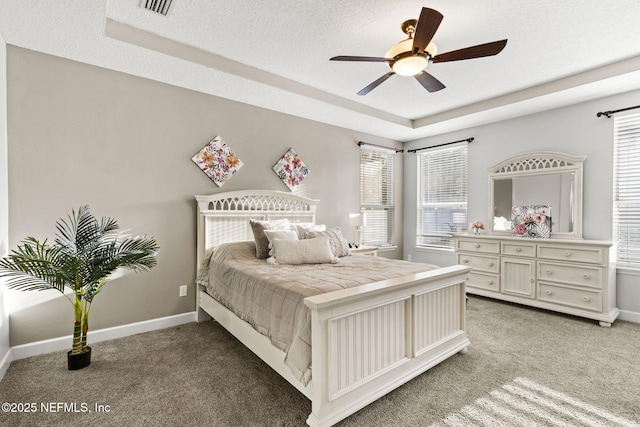 bedroom featuring baseboards, light colored carpet, and a tray ceiling