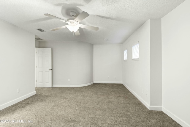 carpeted spare room featuring a ceiling fan, visible vents, a textured ceiling, and baseboards