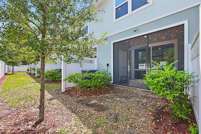 entrance to property featuring stucco siding and fence
