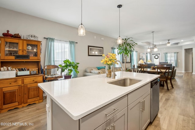 kitchen with open floor plan, light wood-type flooring, stainless steel dishwasher, a sink, and ceiling fan