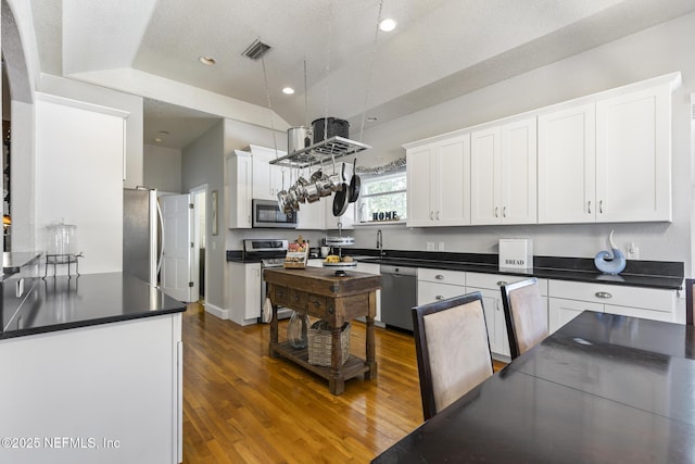 4 Pamela Pkwy, Palm Coast, FL 32137 - kitchen with white cabinetry, dark countertops, stainless steel appliances, and wood finished floors