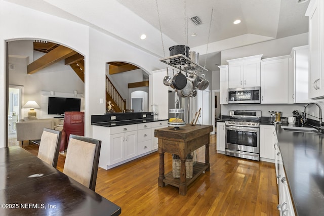 4 Pamela Pkwy, Palm Coast, FL 32137 - kitchen with stainless steel appliances, dark wood finished floors, a sink, dark countertops, and arched walkways