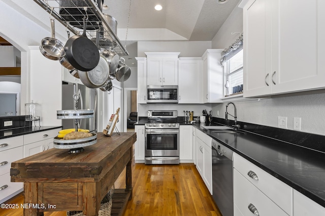 4 Pamela Pkwy, Palm Coast, FL 32137 - kitchen featuring a sink, dark countertops, white cabinets, appliances with stainless steel finishes, and wood finished floors