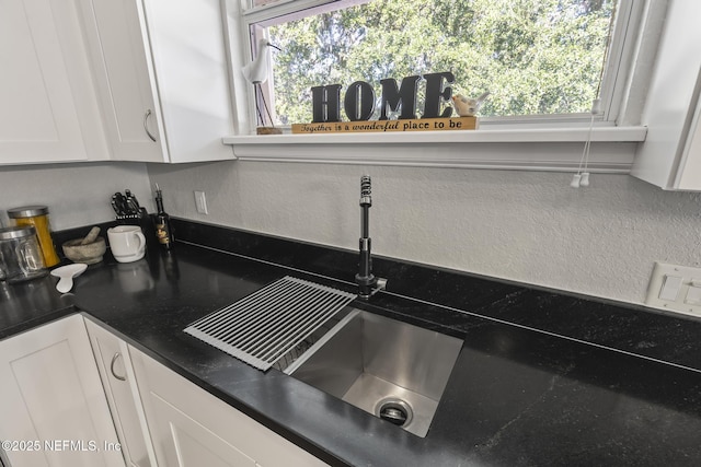 4 Pamela Pkwy, Palm Coast, FL 32137 - interior details with white cabinetry, a textured wall, a sink, and dark countertops