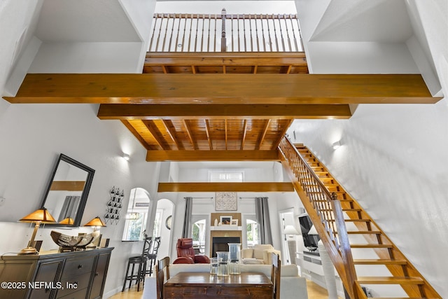 4 Pamela Pkwy, Palm Coast, FL 32137 - staircase featuring arched walkways, a glass covered fireplace, wooden ceiling, and lofted ceiling with beams