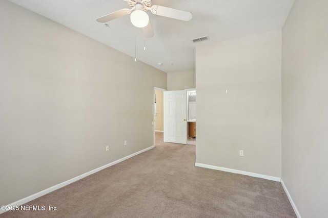 carpeted spare room with visible vents, baseboards, and a ceiling fan
