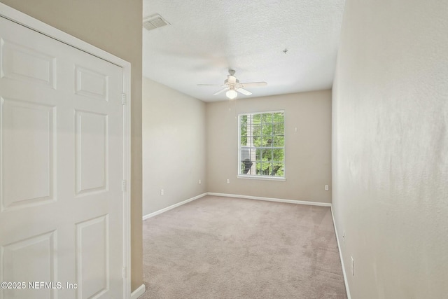 carpeted empty room featuring visible vents, ceiling fan, baseboards, and a textured ceiling