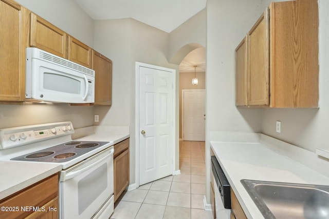 kitchen featuring white appliances, light tile patterned floors, light countertops, arched walkways, and a sink