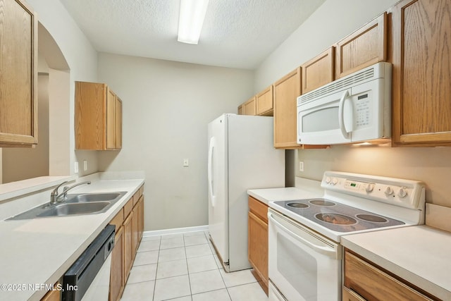 kitchen featuring light countertops, light tile patterned floors, a sink, and white appliances
