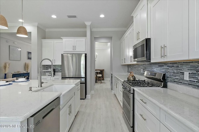 kitchen with visible vents, a sink, crown molding, and stainless steel appliances