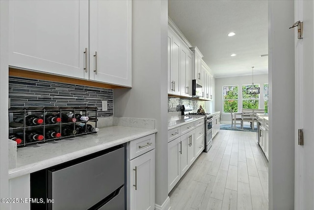 kitchen with decorative backsplash, high end stainless steel range, fridge, recessed lighting, and white cabinets
