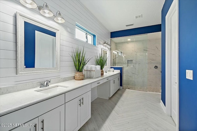 bathroom with double vanity, a sink, a marble finish shower, and wood walls