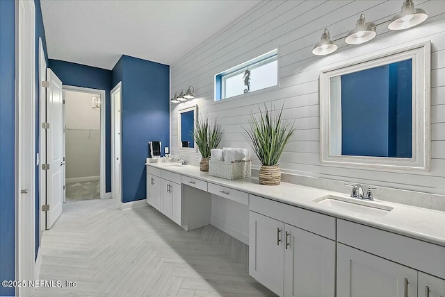 bathroom featuring double vanity, a sink, a walk in closet, and wooden walls