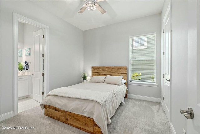bedroom with baseboards, ensuite bath, multiple windows, and light carpet