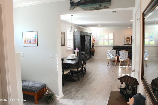 interior space featuring baseboards, light wood-type flooring, visible vents, and ornamental molding