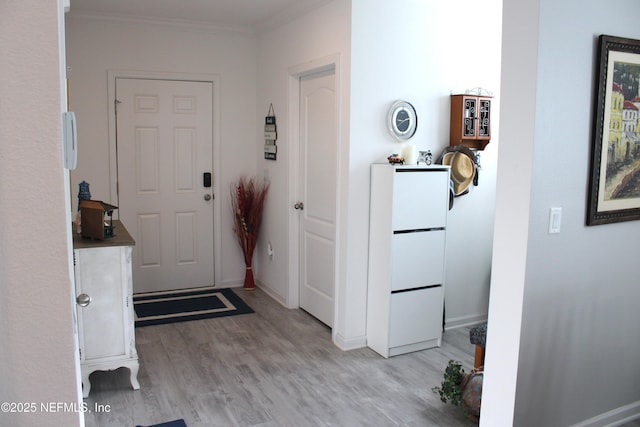 foyer entrance featuring ornamental molding, baseboards, and light wood-style floors