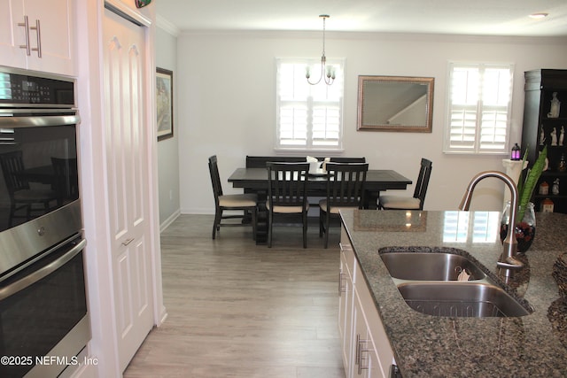 kitchen featuring a wealth of natural light, double oven, crown molding, and a sink