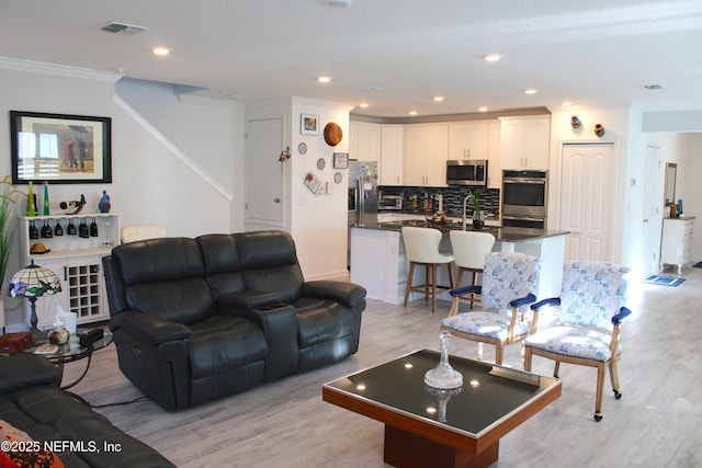 living room with recessed lighting, ornamental molding, light wood-style floors, and visible vents