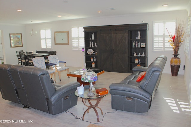 living area with light wood-style flooring, ornamental molding, a healthy amount of sunlight, and recessed lighting