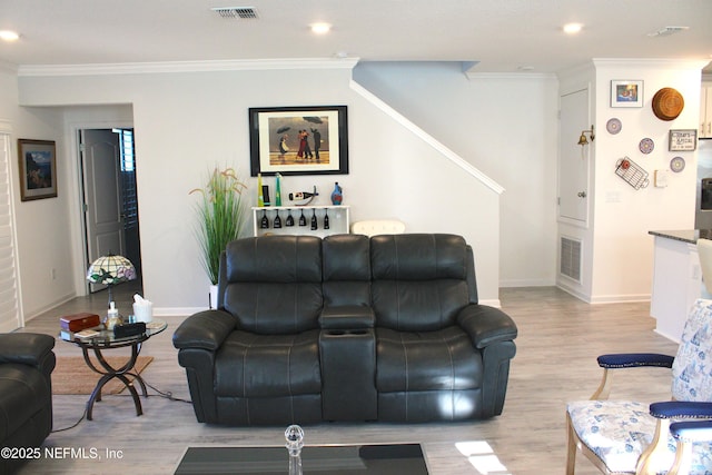 living room featuring light wood-style flooring, crown molding, and visible vents