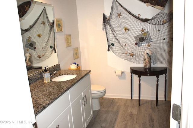 bathroom with baseboards, toilet, wood finished floors, and vanity