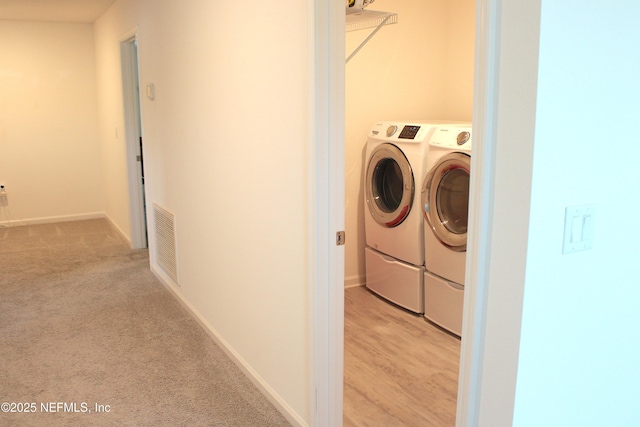 laundry room featuring baseboards, washing machine and clothes dryer, visible vents, light carpet, and laundry area