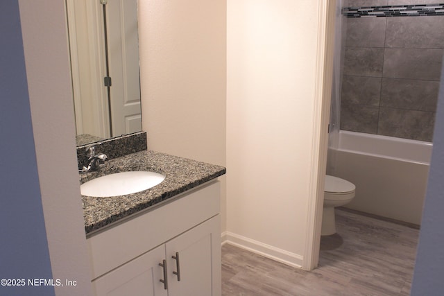 bathroom featuring baseboards, wood finished floors, toilet, and vanity