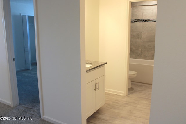 bathroom featuring toilet, vanity, baseboards, and wood finished floors