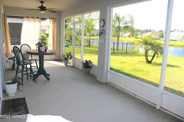 sunroom / solarium featuring a water view and a ceiling fan