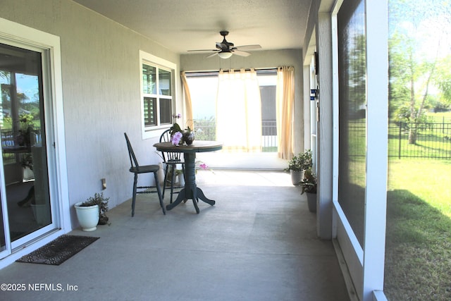 sunroom with concrete floors, a textured ceiling, a textured wall, and a ceiling fan