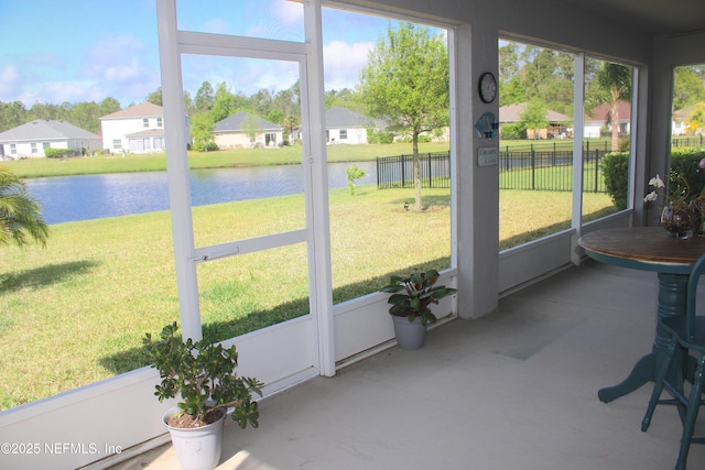 sunroom featuring a water view, a wealth of natural light, and a residential view