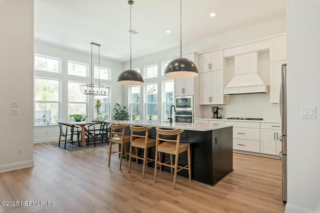 508 Palm Crest Dr, Ponte Vedra, FL 32081 - kitchen with premium range hood, light wood finished floors, appliances with stainless steel finishes, light countertops, and an island with sink