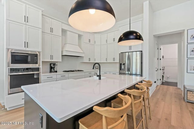 508 Palm Crest Dr, Ponte Vedra, FL 32081 - kitchen featuring appliances with stainless steel finishes, custom range hood, light wood-style flooring, a breakfast bar area, and light countertops