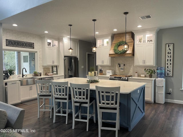 104 W Grandview Dr, East Palatka, FL 32131 - kitchen with custom exhaust hood, visible vents, white cabinets, a sink, and appliances with stainless steel finishes